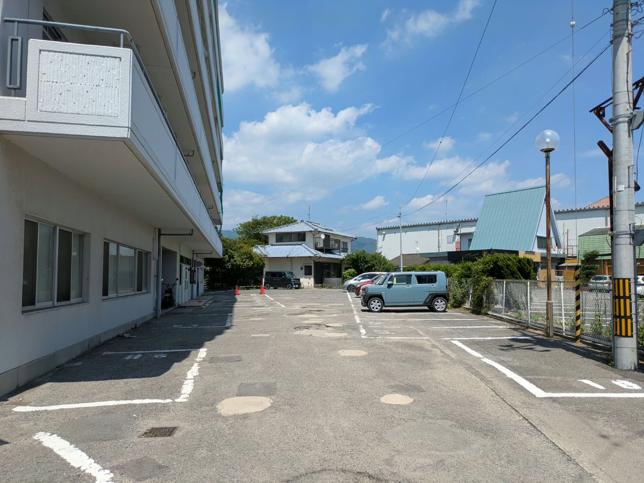 マンション駐車場の奥に見えるおきたま整体院の一軒家